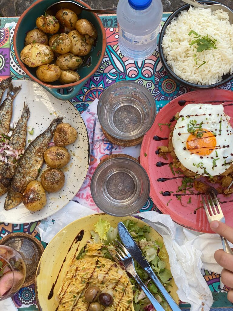 Traditional Portuguese meal spread with grilled fish pasteis de nata and vinho verde in Lisbon