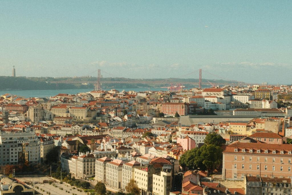A stunning panoramic view of Lisbon featuring the 25 de Abril Bridge and Cristo Rei statue.